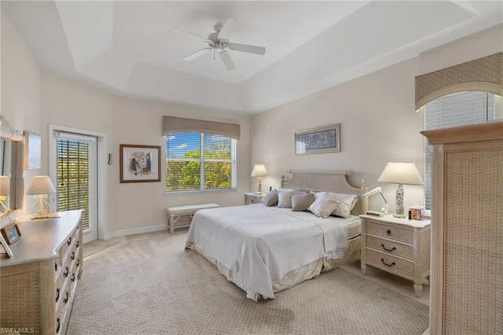 Carpeted bedroom featuring a raised ceiling and a ceiling fan