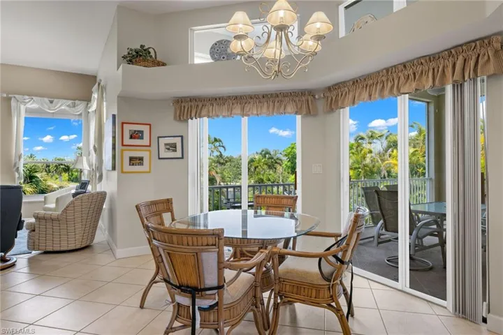 Dining room with light tile patterned flooring, a chandelier, and a high ceiling