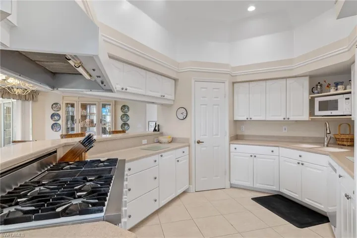 Kitchen with premium range hood, white cabinetry, white appliances, light countertops, and light tile patterned floors