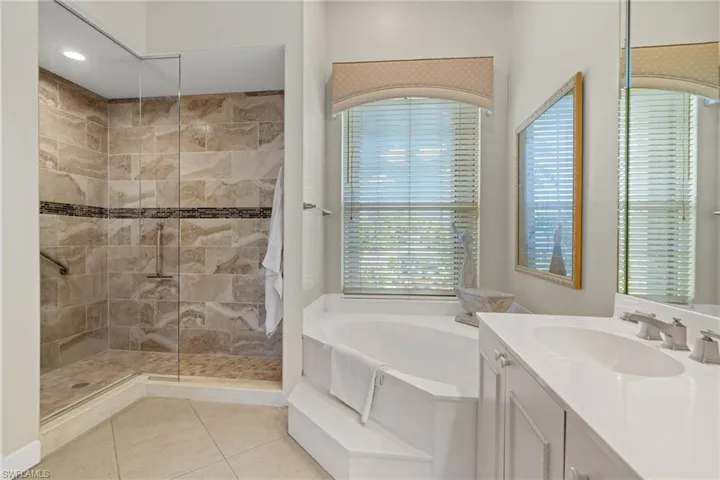 Bathroom with a garden tub, vanity, light tile patterned floors, and walk in shower