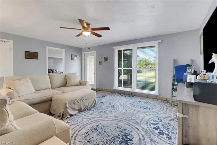 Tiled living room with ceiling fan and baseboards