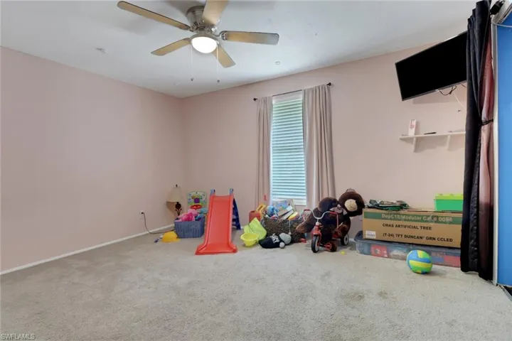 Recreation room featuring carpet flooring, baseboards, and ceiling fan