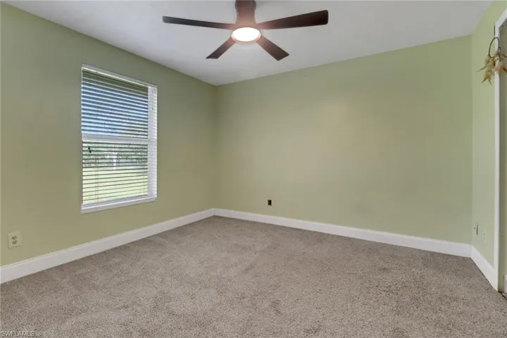 Unfurnished room featuring carpet flooring, baseboards, and ceiling fan