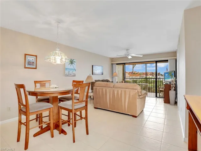 Dining Area and Living Room with Ceiling Fan and Sliders Leading to the Screened Tiled Lanai with Bay View