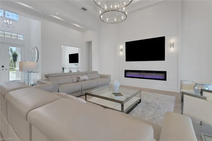 Living area featuring a chandelier, a glass covered fireplace, and plenty of natural light
