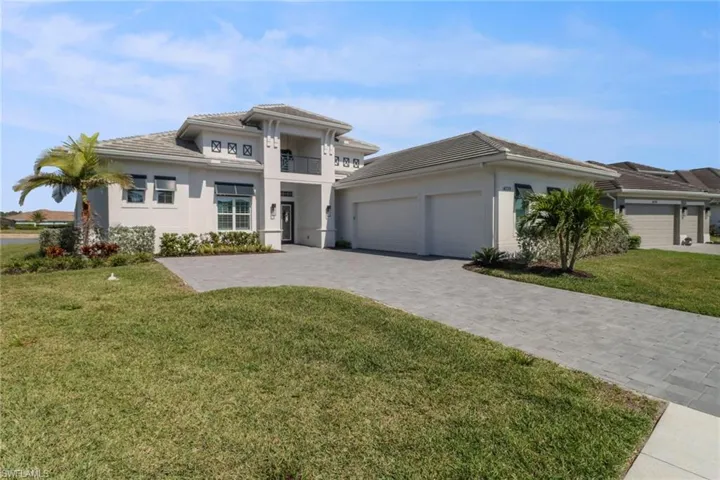 View of front of home with a  3 car garage, long driveway, a front yard, stucco siding, and a tile roof