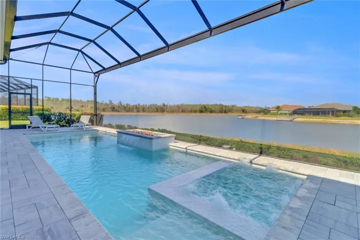 View of swimming pool with a pool with connected hot tub, fire feature, waterfall, a water view, a patio, and a lanai