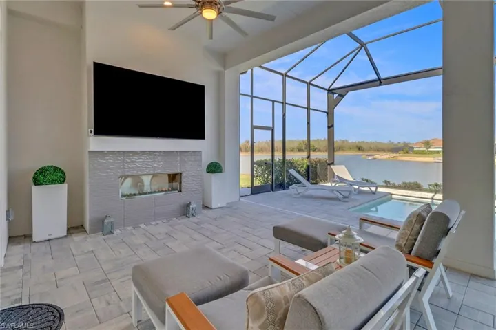 View of patio featuring ceiling fan, an outdoor pool, a lanai, and a fireplace