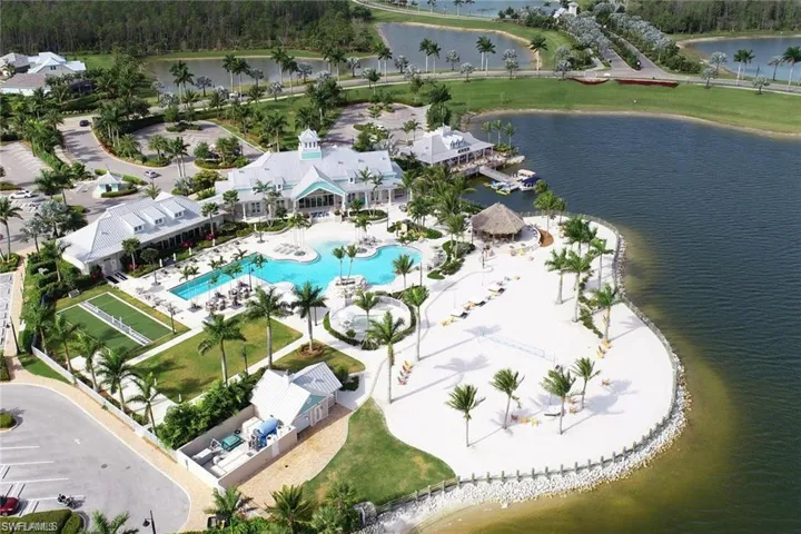 Ariel shot of Naples Reserve amenity center with Pool, lap pool, exercise room, bocci courts, outdoor bar, volley ball net, beach area, outrigger building, boat docks. All facing large lake.