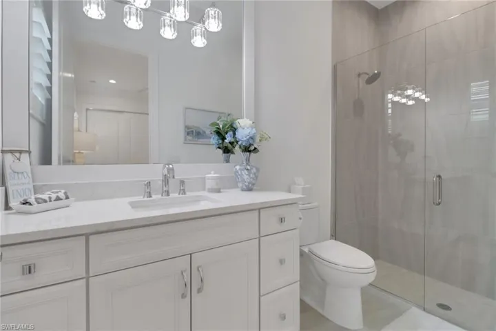 4th bedrooms on suite full bath featuring a stall shower, vanity, and tile patterned flooring