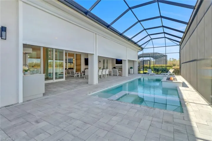 View of pool with a patio, a pool with connected hot tub and storm smart shutters.
