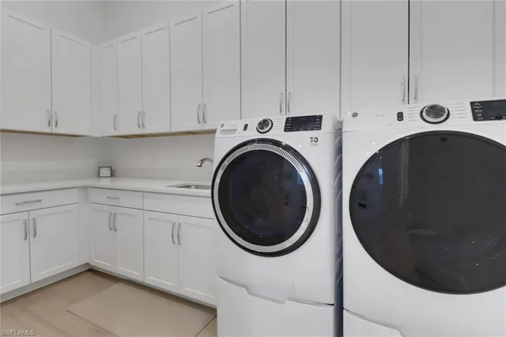 Laundry area with washing machine and clothes dryer, cabinet space, and light wood finished floors