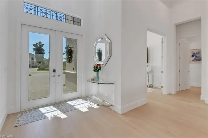 Entryway with wood  floors, French entry doors, and a towering ceiling