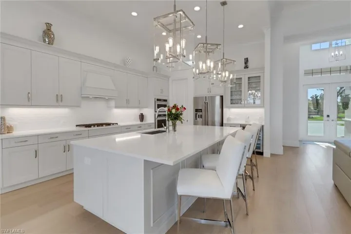 Kitchen with stainless steel appliances, custom range hood, pendant lights, light wood-type flooring, and recessed lighting