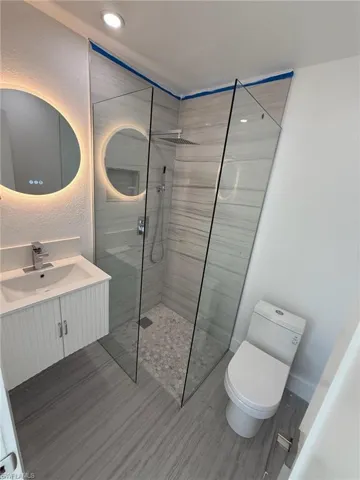 Bathroom featuring a textured wall, walk in shower, and vanity