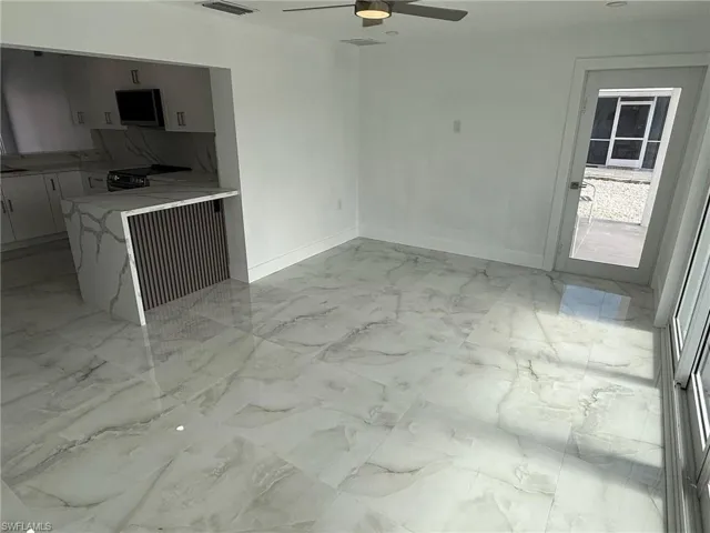 Unfurnished living room featuring a ceiling fan and baseboards