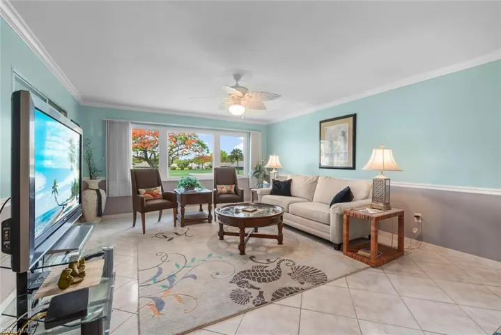 Spacious living area featuring tile flooring, a multi-pane window, and crown molding