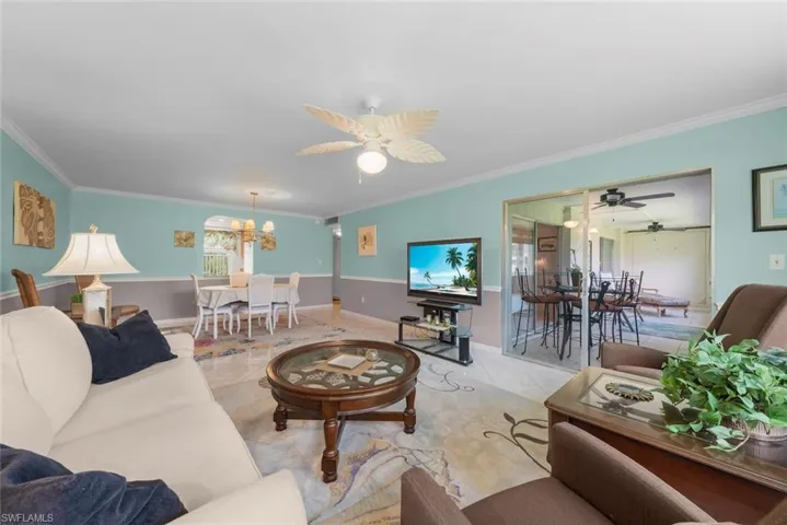 Spacious living area featuring tile flooring, crown molding, and a decorative ceiling fan