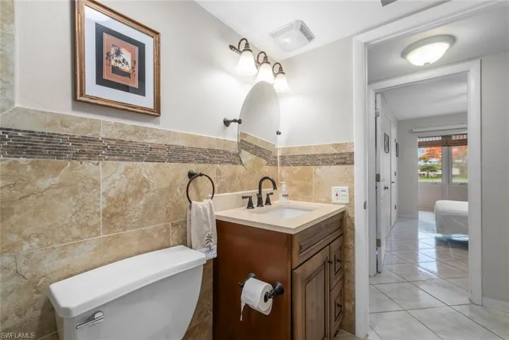Bathroom featuring a wood-finish vanity with an integrated sink, a dark bronze faucet, and an oval mirror