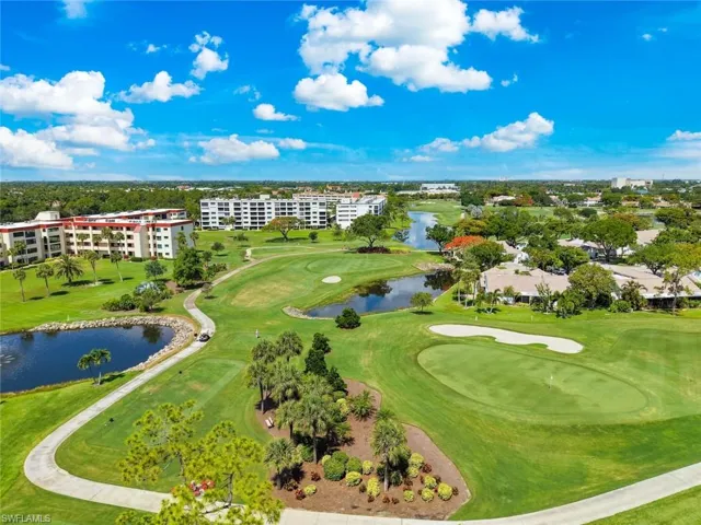 Expansive golf course setting featuring manicured greens, water features, mature trees, and golf cart paths