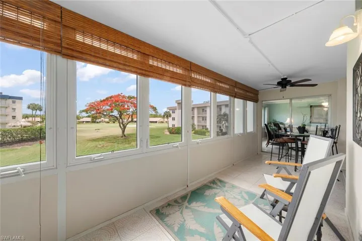 Enclosed sun room featuring windows with natural wood blinds, a ceiling fan, and tile flooring
