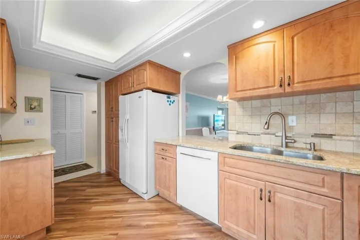 Kitchen featuring laminate flooring, light wood cabinetry, and a tile backsplash