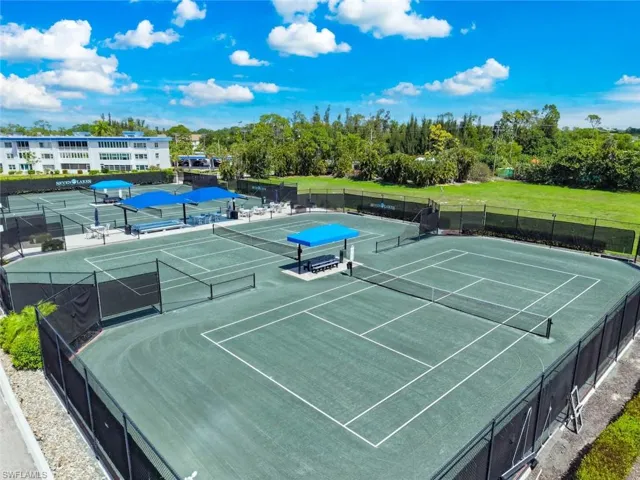 Multiple tennis courts featuring green playing surfaces and black perimeter fencing