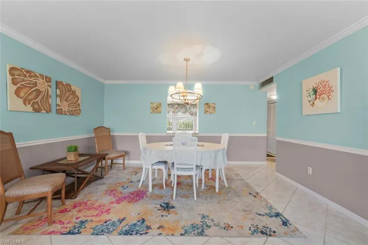 Dining area featuring tile flooring, crown molding, and a chandelier lighting fixture