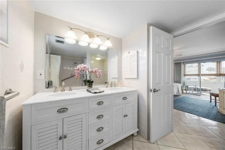 Primary bathroom featuring a double vanity with louvered cabinetry, two integrated sinks, and brushed nickel fixtures