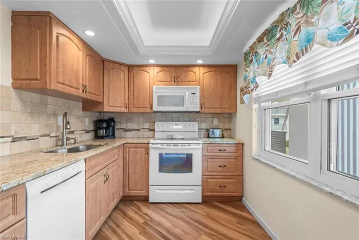 Kitchen featuring light wood-finish cabinetry, light-toned countertops, and a tile backsplash