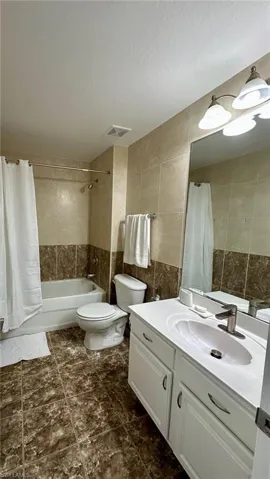 Bathroom with vanity, tile walls, a textured ceiling, and shower / bath combination with curtain