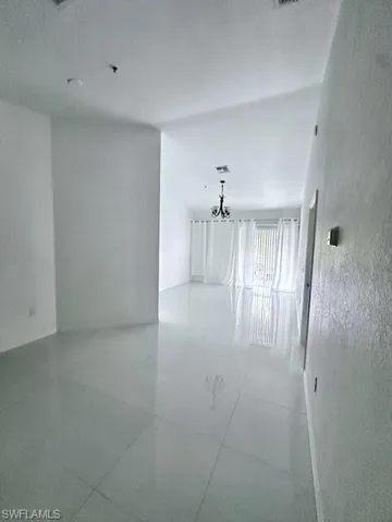 Unfurnished room featuring a chandelier, a textured wall, and a textured ceiling