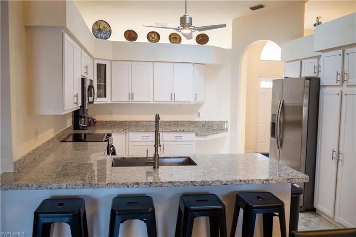 Kitchen featuring visible vents, white cabinets, a breakfast bar, a peninsula, and a sink