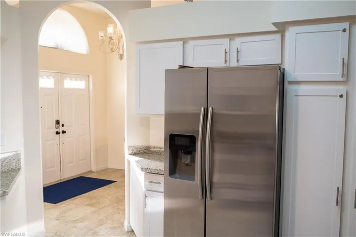 Kitchen featuring white cabinetry, stainless steel fridge with ice dispenser, and light stone countertops