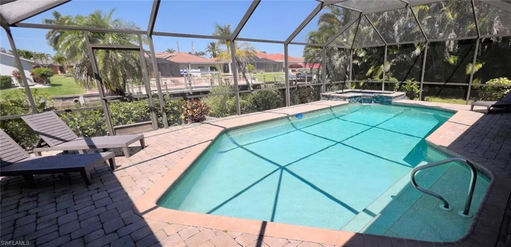 View of pool featuring a patio, a residential view, a pool with connected hot tub, and screen enclosure