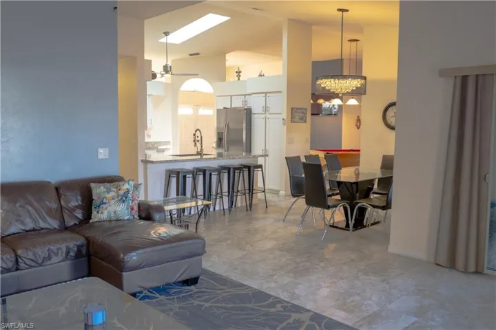 Living area with high vaulted ceiling, an inviting chandelier, and baseboards