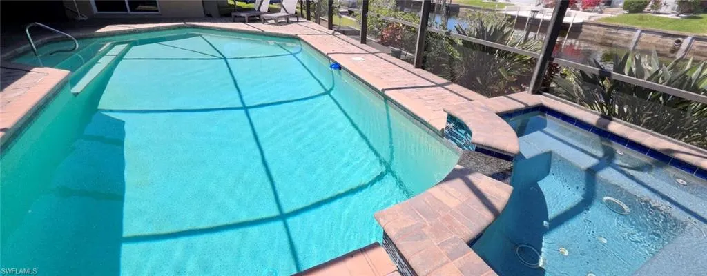 View of swimming pool with connected hot tub and lanai