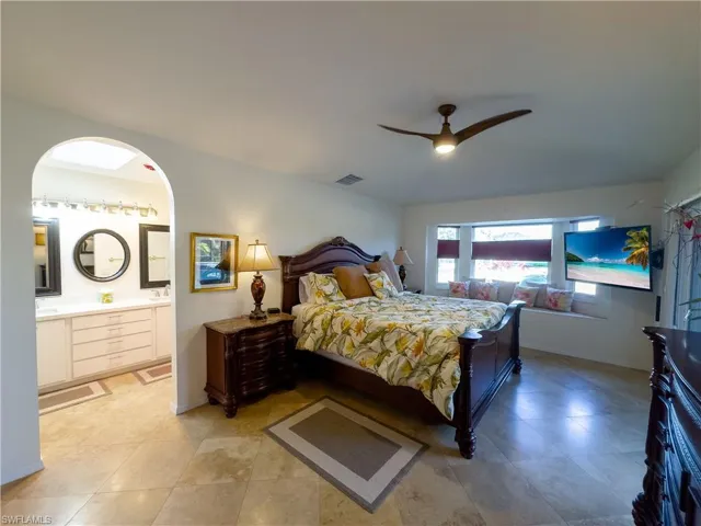 Bedroom with ensuite bathroom, visible vents, a ceiling fan, and baseboards