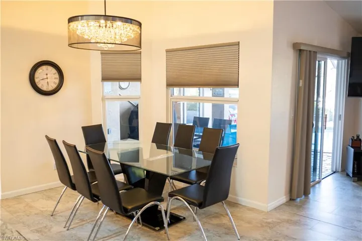 Dining space featuring vaulted ceiling, baseboards, and an inviting chandelier