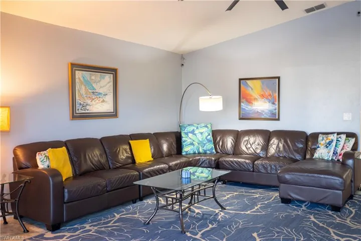 Living area with vaulted ceiling, ceiling fan, and visible vents