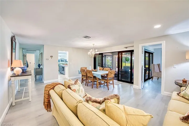 Living room with a chandelier, light wood-type flooring, and recessed lighting