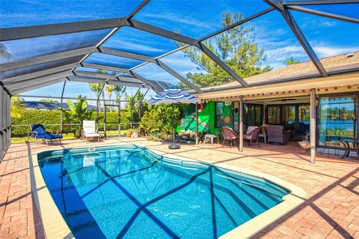 Swimming pool featuring a patio, a sunroom, and glass enclosure