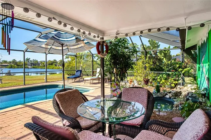 View of patio / terrace with a sunroom, an outdoor pool, a water view, a lanai, and outdoor dining area