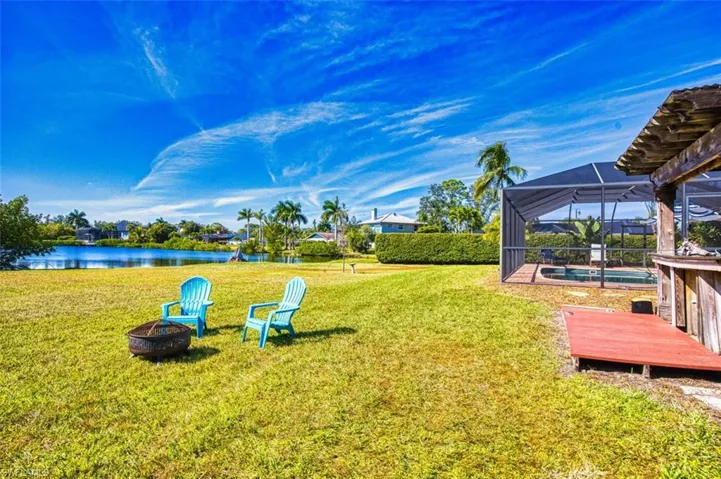 View of grassy yard with a lanai, an outdoor pool, a fire pit, a sunroom, and a deck with water view