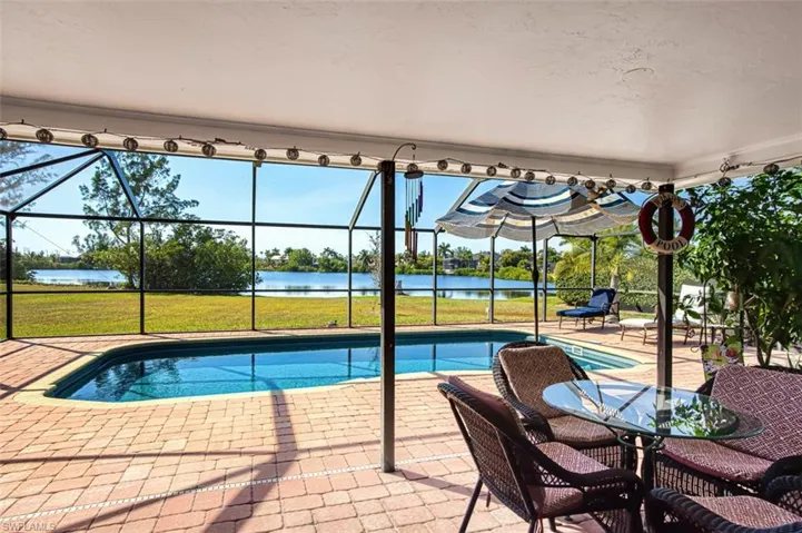Swimming pool featuring a sunroom, a lanai, a water view, and a patio area