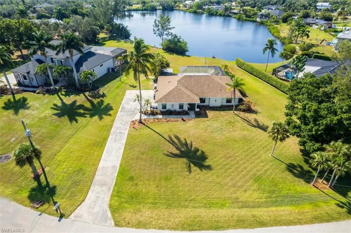 Aerial view of property and surrounding area featuring a nearby body of water and a tree filled landscape