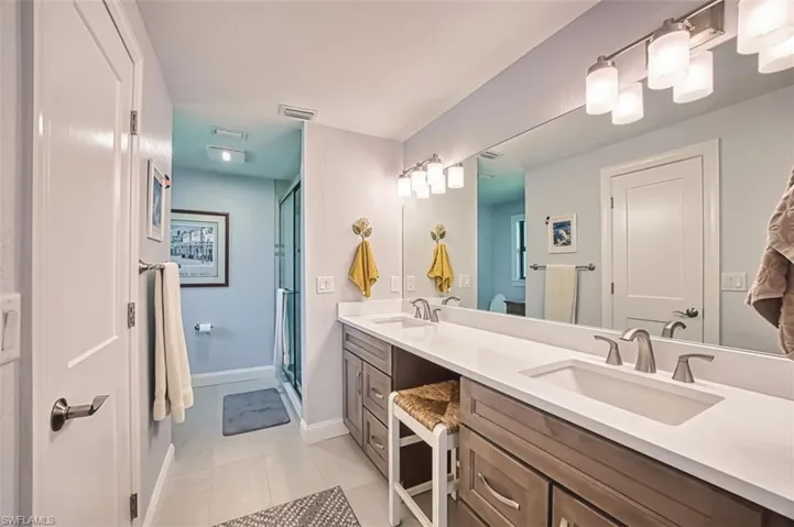 Full bathroom featuring double vanity, a shower stall, and light tile patterned flooring