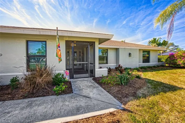 Doorway to property featuring a sunroom, stucco siding, and a lawn