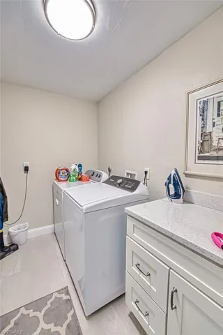 Laundry area with washer and clothes dryer, cabinet space, and light tile patterned flooring