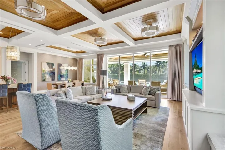 Living room featuring coffered ceiling, light wood-style floors, and suspended lighting